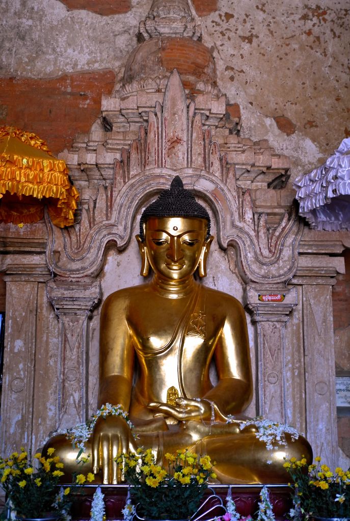Painted gold Buddha statue in a temple niche in Myanmar