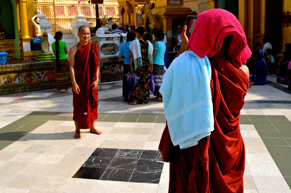 Monk taking picture of another monk with a smartphone at Shwedagon Pagoda in Yangon, Myanmar