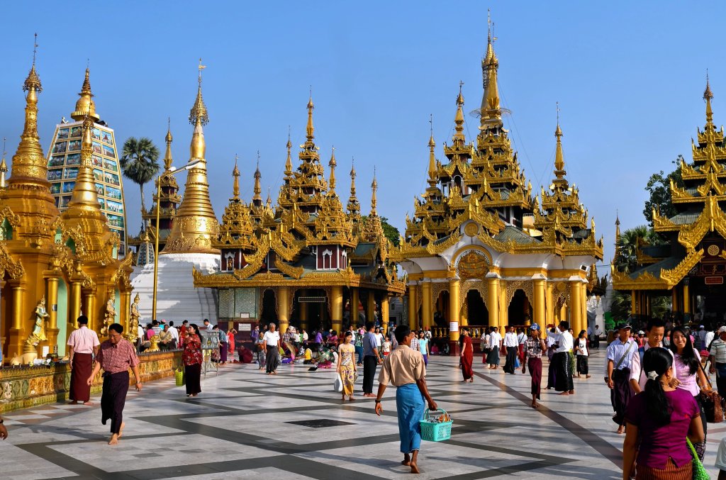 The many niches of Shwedagon Pagoda with people walking around the pavillion in Yangon, Myanmar