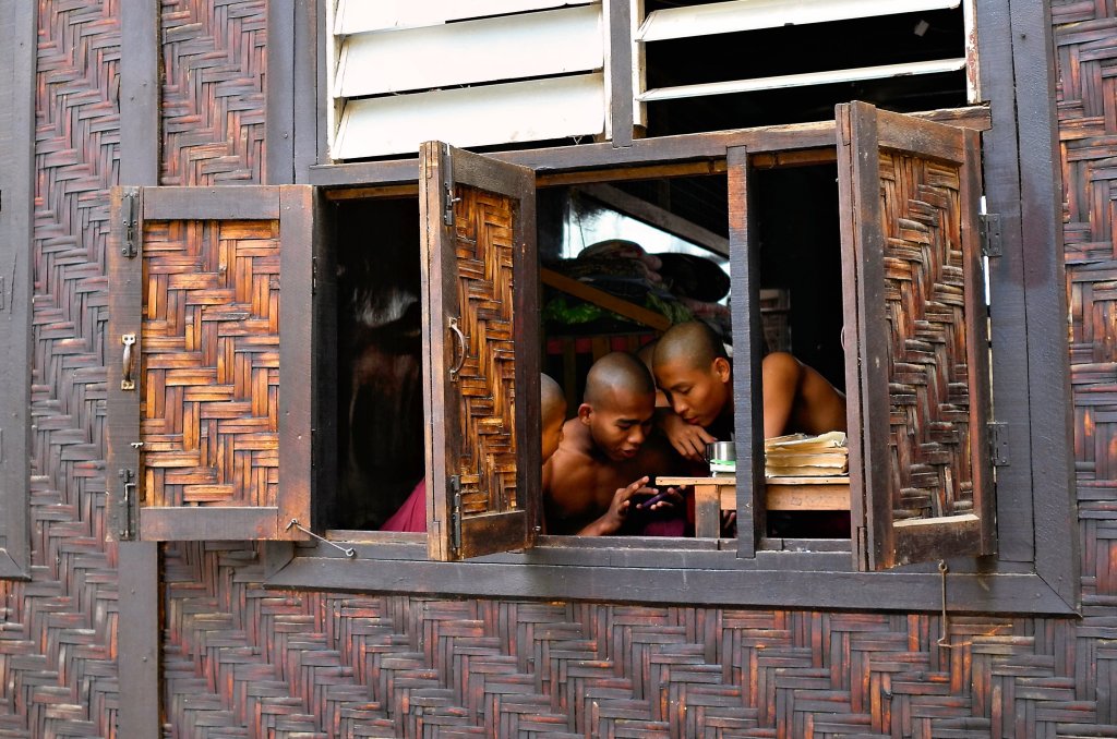 Young monks in their quarters crowded around a smartphone in Myanmar